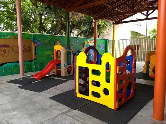 Parquinho coberto do colégio, com escorregadores e brinquedos coloridos
