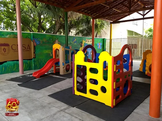 Parquinho coberto do colégio, com escorregadores e brinquedos coloridos